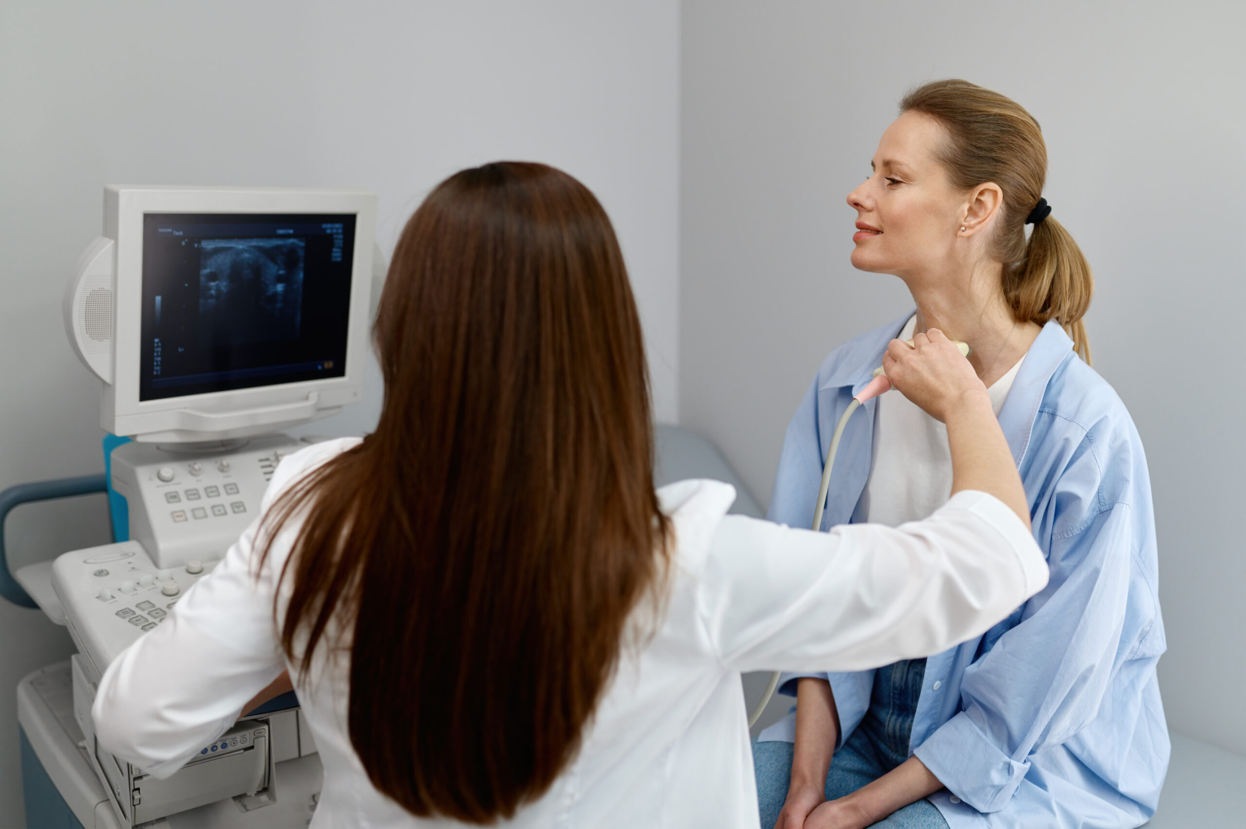 A doctor performs an ultrasound scan of the thyroid gland and lymph nodes. 