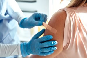 A nurse place a band-aid before vaccinating a teenager.